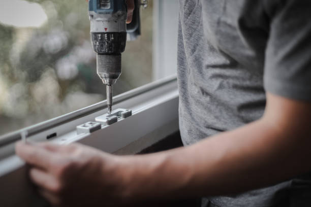 A man installing something on a window sill with a screwdriver